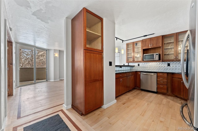 kitchen featuring brown cabinetry, light wood finished floors, and appliances with stainless steel finishes