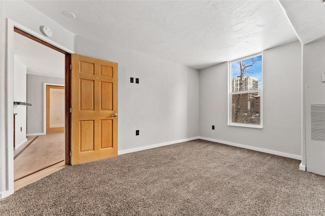 spare room featuring baseboards, a textured ceiling, and carpet floors