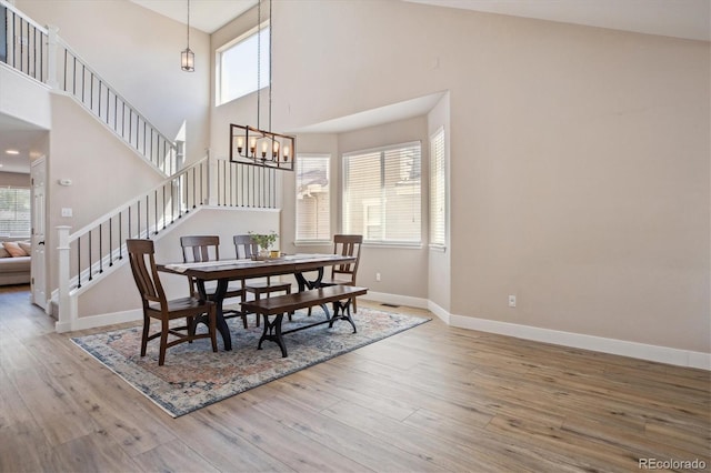 dining room featuring wood finished floors, baseboards, a towering ceiling, and healthy amount of natural light