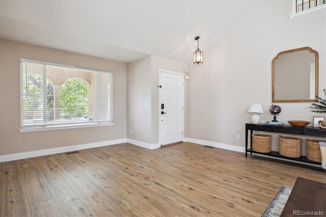 foyer featuring healthy amount of natural light, wood finished floors, baseboards, and high vaulted ceiling