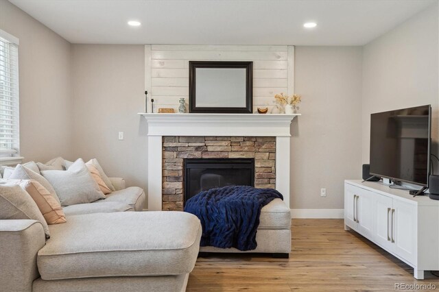 living room featuring light wood-style floors, a fireplace, recessed lighting, baseboards, and plenty of natural light