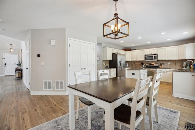 dining area with a chandelier, light wood-style flooring, baseboards, and recessed lighting