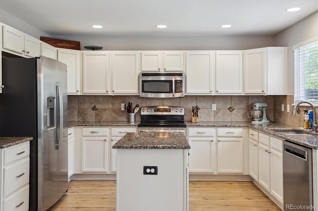 kitchen featuring appliances with stainless steel finishes, a sink, a center island, white cabinetry, and recessed lighting