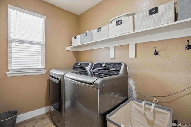 clothes washing area featuring washing machine and dryer, plenty of natural light, wood finished floors, and baseboards