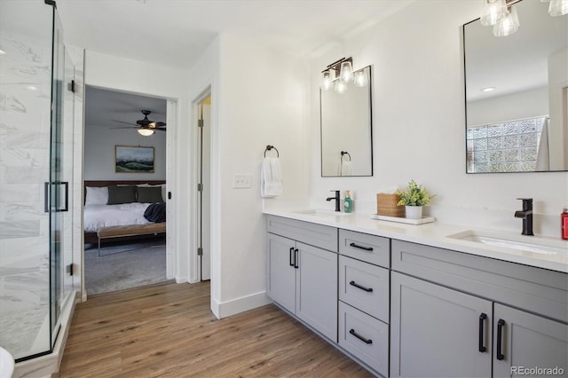 bathroom featuring a shower stall, wood finished floors, double vanity, ceiling fan, and ensuite bathroom