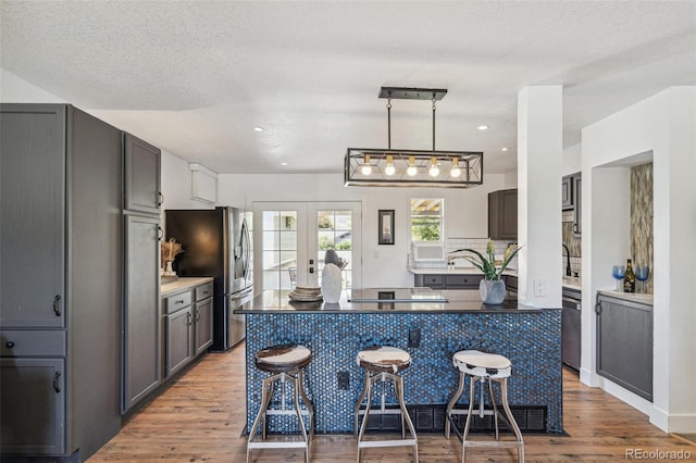 18355 W 59th Dr, Golden, CO 80403 - kitchen with stainless steel fridge, light wood-style flooring, a kitchen island, a kitchen bar, and decorative backsplash