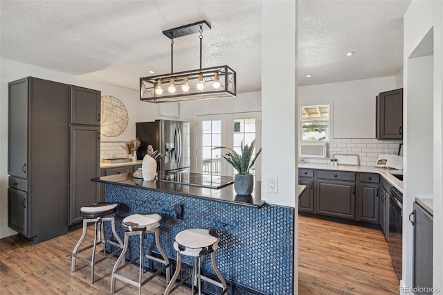 18355 W 59th Dr, Golden, CO 80403 - kitchen featuring stainless steel fridge with ice dispenser, black electric stovetop, a kitchen bar, light wood-type flooring, and tasteful backsplash
