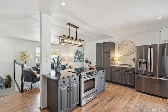 18355 W 59th Dr, Golden, CO 80403 - kitchen featuring stainless steel appliances, light wood-style floors, dark countertops, tasteful backsplash, and recessed lighting
