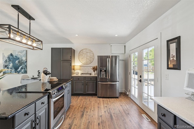 18355 W 59th Dr, Golden, CO 80403 - kitchen with appliances with stainless steel finishes, french doors, light wood-style flooring, dark stone countertops, and recessed lighting