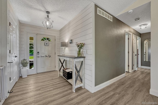 1572 W Long Ave, Littleton, CO 80120 - entrance foyer featuring a textured ceiling, light wood-type flooring, a chandelier, and wood walls