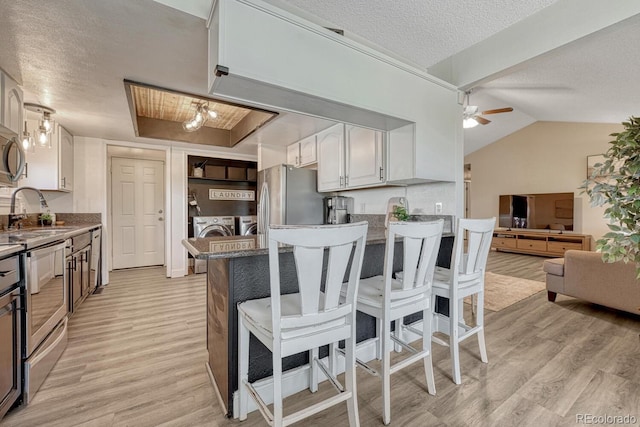1572 W Long Ave, Littleton, CO 80120 - kitchen featuring separate washer and dryer, a textured ceiling, light wood finished floors, a breakfast bar, and a ceiling fan