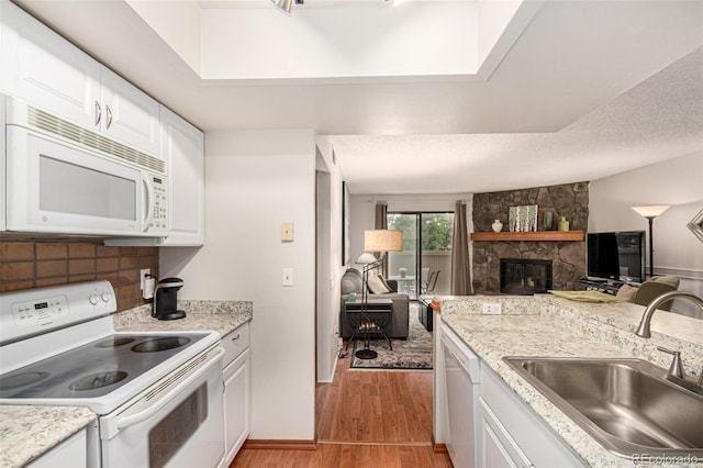 7750 W 87th Dr Unit C, Arvada, CO 80005 - kitchen with white appliances, open floor plan, a stone fireplace, light wood finished floors, and white cabinets