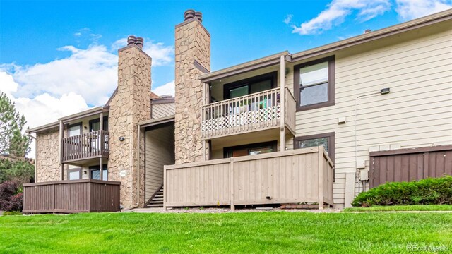 7750 W 87th Dr Unit C, Arvada, CO 80005 - rear view of property featuring a lawn, stone siding, and a balcony
