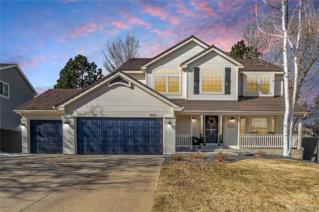 traditional-style house with a porch, an attached garage, and driveway