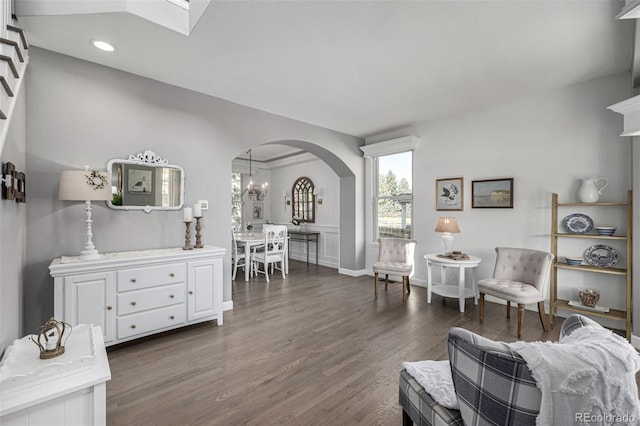 living room featuring dark wood-type flooring, a notable chandelier, recessed lighting, and arched walkways