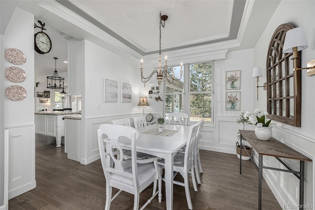 dining room featuring a decorative wall, a raised ceiling, an inviting chandelier, and ornamental molding