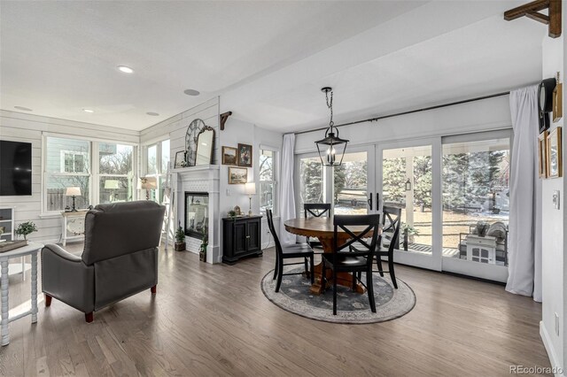 dining area featuring wood finished floors, a glass covered fireplace, recessed lighting, french doors, and wooden walls