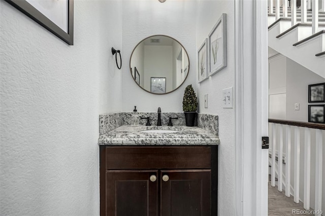 bathroom featuring wood finished floors, vanity, and a textured wall