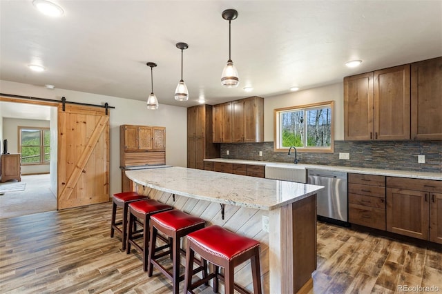 116 County Road 414, Granby, CO 80446 - kitchen with stainless steel dishwasher, a barn door, wood finished floors, decorative backsplash, and recessed lighting