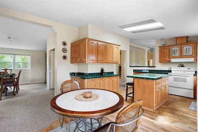 116 County Road 414, Granby, CO 80446 - kitchen with white electric range, tile counters, under cabinet range hood, and brown cabinetry