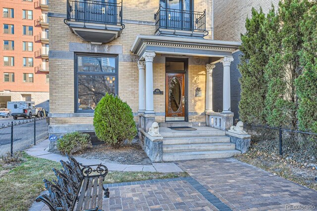 view of exterior entry with central AC unit and a balcony