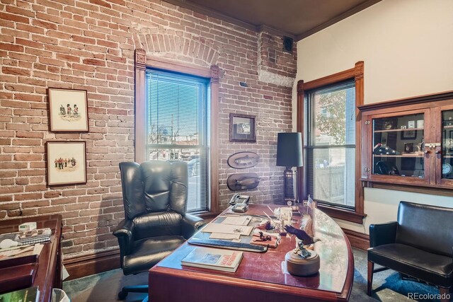 office space with ornamental molding and brick wall