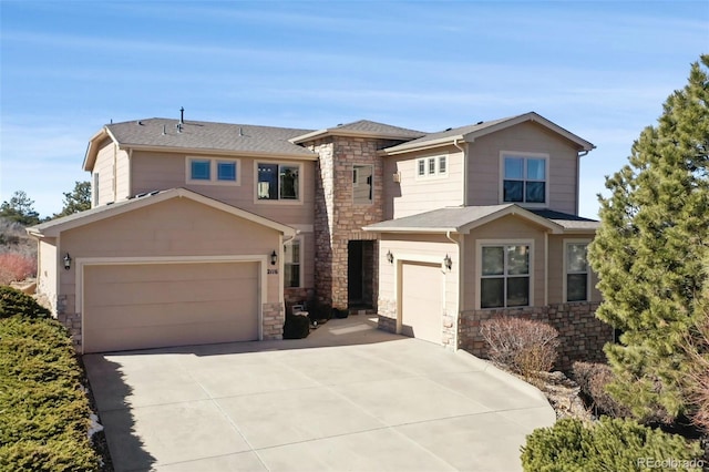 view of front facade featuring a shingled roof, stone siding, driveway, and an attached garage