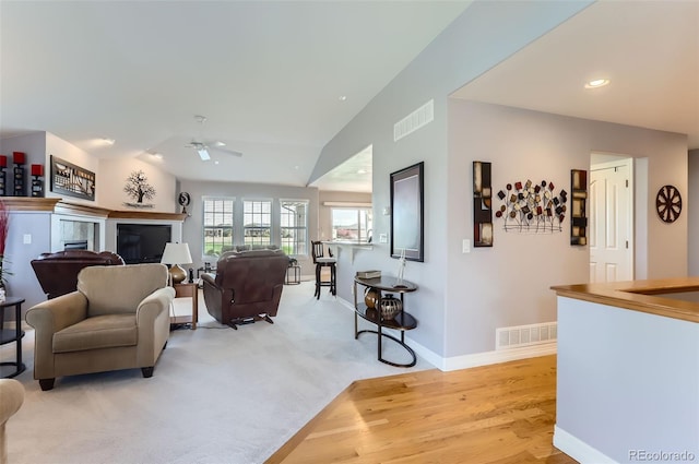living area featuring a ceiling fan, baseboards, visible vents, and lofted ceiling