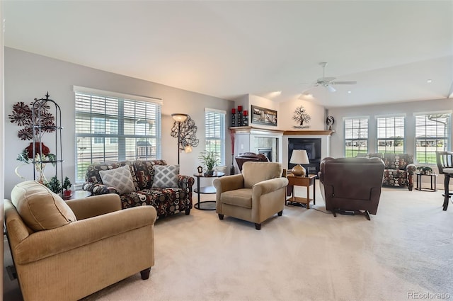 living area featuring a ceiling fan, light colored carpet, a healthy amount of sunlight, and vaulted ceiling