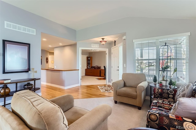 living room featuring a ceiling fan, lofted ceiling, light wood-type flooring, and visible vents