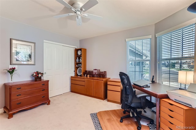 office space with light carpet and a ceiling fan