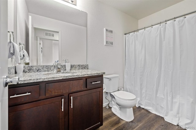 full bath with a shower with curtain, visible vents, wood finished floors, vanity, and toilet