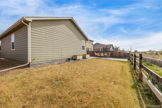 view of property exterior featuring a lawn, a patio area, and fence