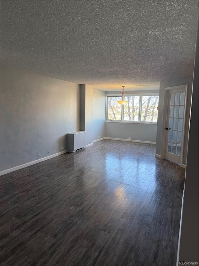 spare room with dark wood-style floors, baseboards, and a textured ceiling