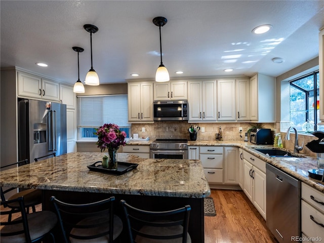 8908 Jellison Ct, Westminster, CO 80021 - kitchen featuring high end appliances, a sink, a kitchen breakfast bar, light wood-style flooring, and decorative backsplash