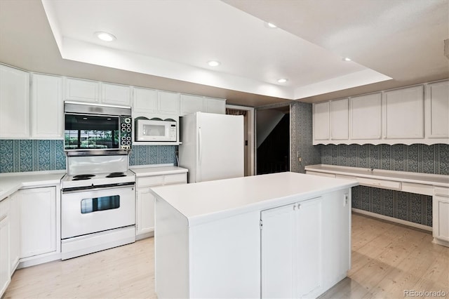 7129 S Marshall St, Littleton, CO 80128 - kitchen with white appliances, a raised ceiling, light wood-type flooring, white cabinetry, and recessed lighting
