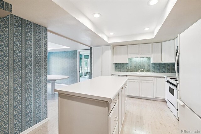7129 S Marshall St, Littleton, CO 80128 - kitchen featuring white appliances, light wood-style floors, a kitchen island, white cabinetry, and a tray ceiling