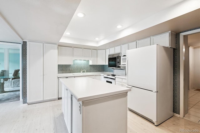 7129 S Marshall St, Littleton, CO 80128 - kitchen with white appliances, light wood-style floors, white cabinetry, light countertops, and a kitchen island
