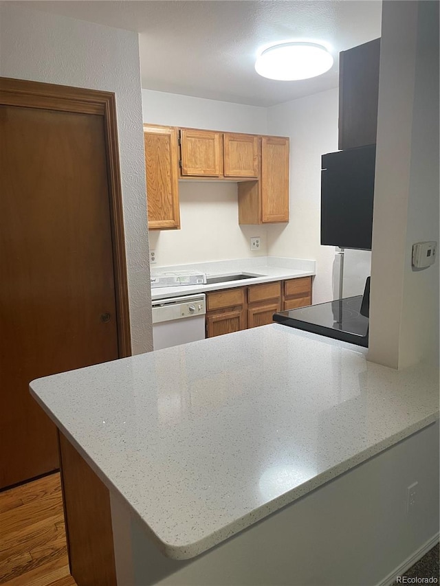 kitchen featuring hardwood / wood-style flooring, light stone countertops, white dishwasher, and kitchen peninsula