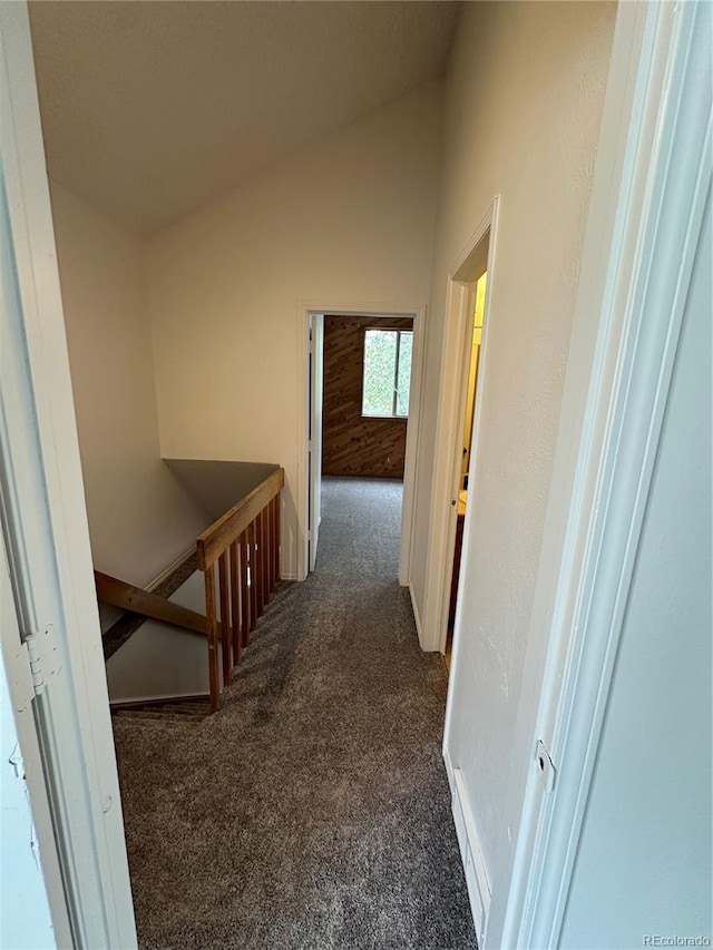 corridor with lofted ceiling and dark carpet