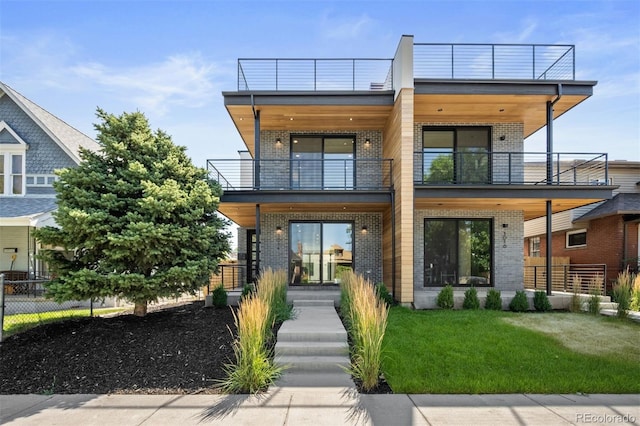 modern home featuring a front yard and a balcony