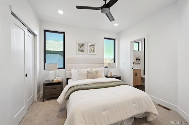 carpeted bedroom with connected bathroom, multiple windows, and ceiling fan