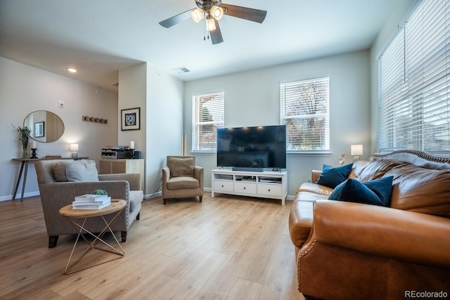 living area featuring visible vents, light wood finished floors, baseboards, and a ceiling fan