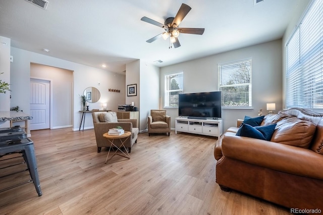 living room featuring light wood-style floors, visible vents, a ceiling fan, and baseboards