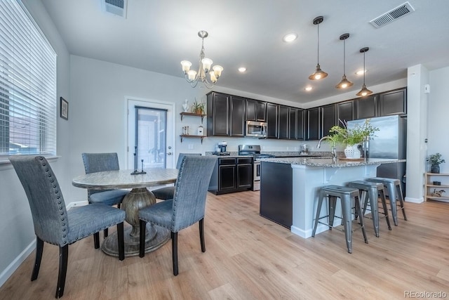 kitchen with light wood-style flooring, visible vents, appliances with stainless steel finishes, and an inviting chandelier