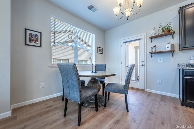 dining area featuring light wood-type flooring, baseboards, visible vents, and a chandelier