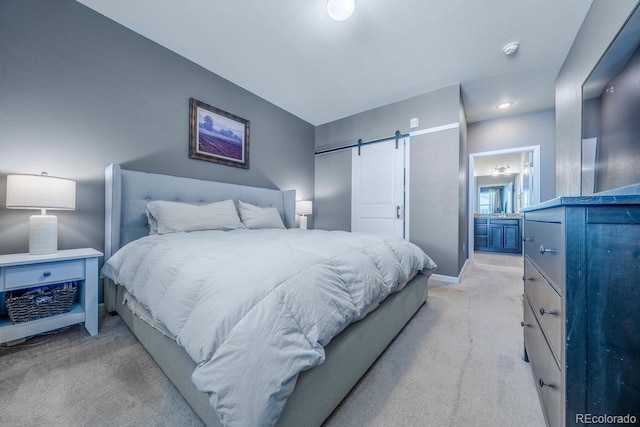 bedroom with light carpet, ensuite bathroom, baseboards, and a barn door