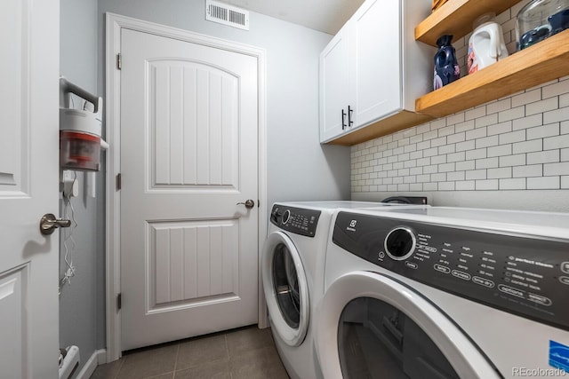 clothes washing area featuring cabinet space, visible vents, and washer and clothes dryer