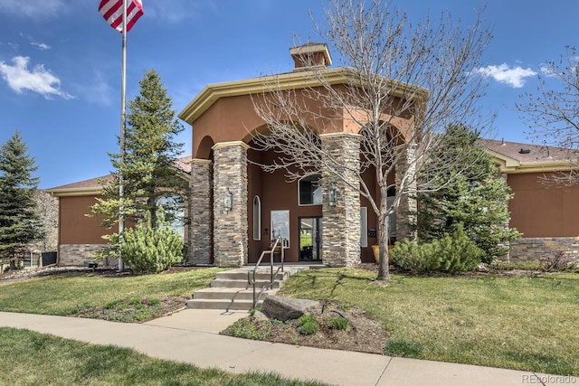 view of front of property featuring stucco siding, a chimney, stone siding, and a front yard
