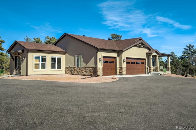 view of front facade with stucco siding, aphalt driveway, stone siding, roof with shingles, and an attached garage